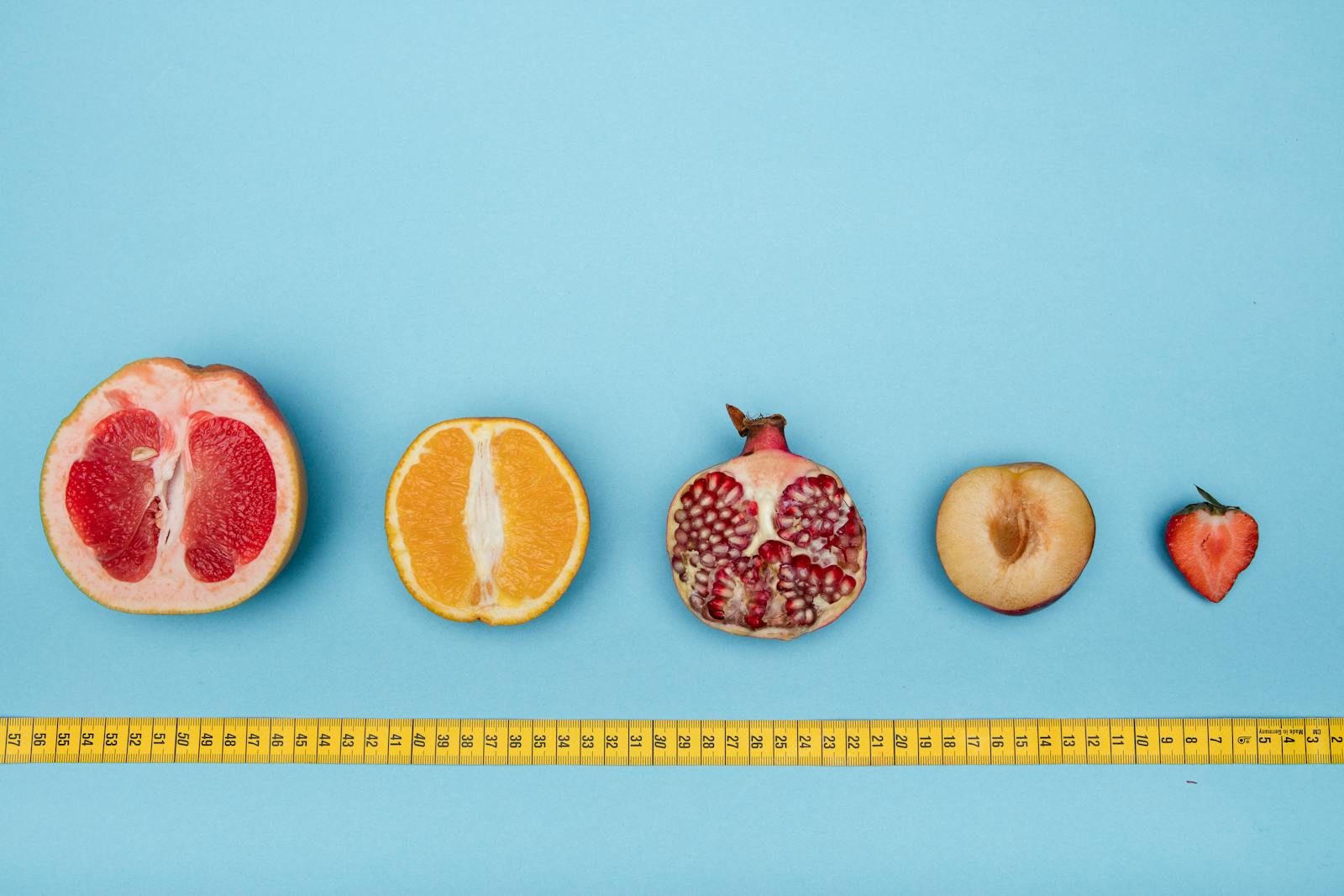 Colorful halved fruits lined up against a light blue background with measuring tape, perfect for healthy lifestyle themes.